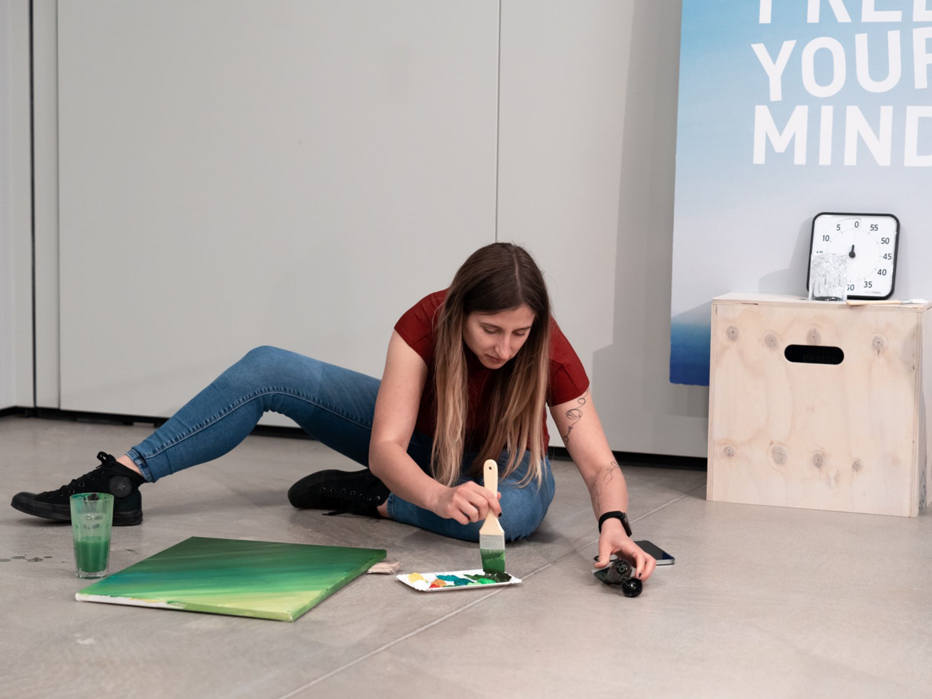 Teilnehmerin sitzt auf dem Boden und malt auf eine Leinwand